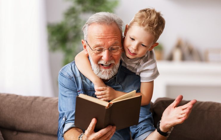 . Cheerful grandfather and grandson reading book together