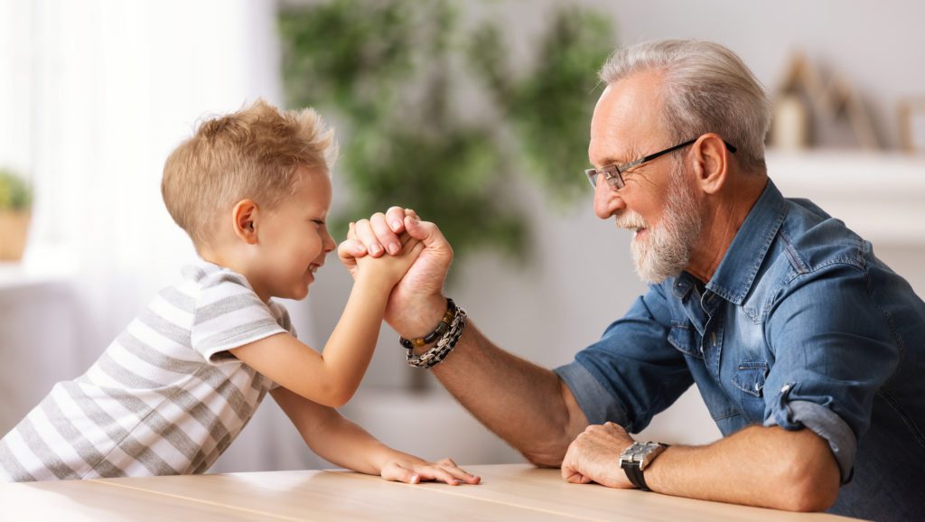 Grandfather arm wrestling with grandson